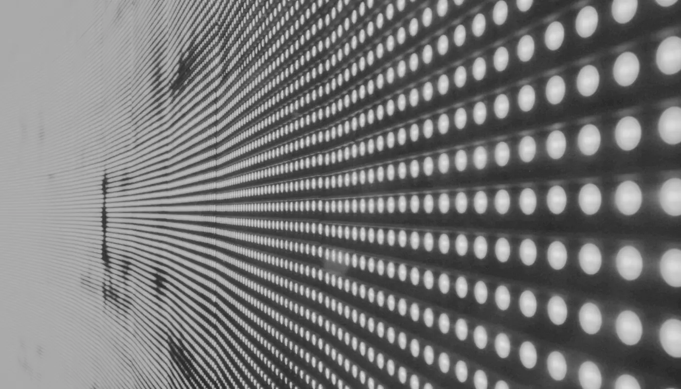 Close-up of a patterned surface with numerous small, round lights like a software M&A advisors insights. These lights are arranged in rows, creating a perspective effect that appears to extend into the distance, uniformly spaced across the surface and emitting a bright, white glow.